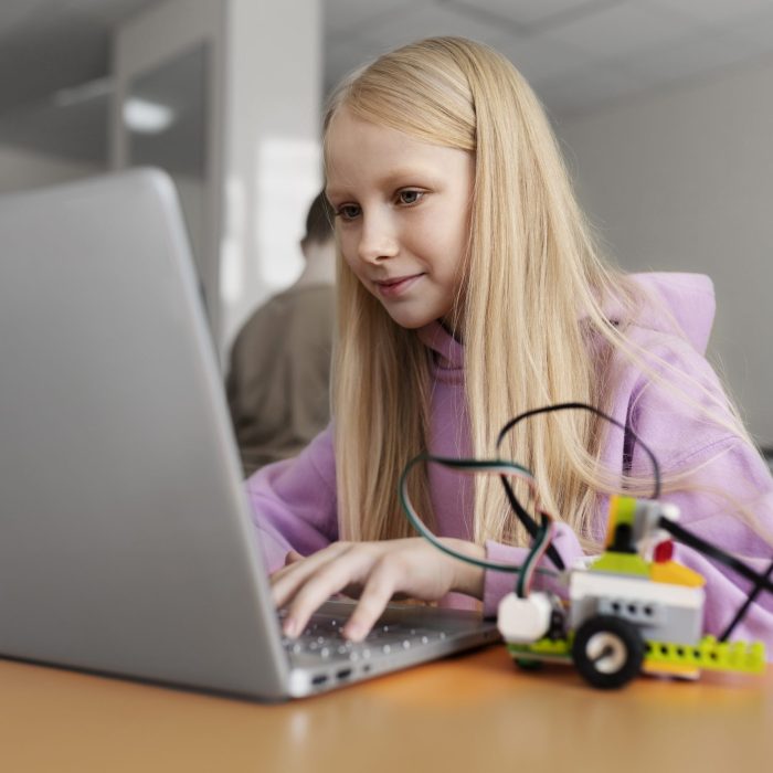 young-girl-using-laptop-electronic-parts-build-robot